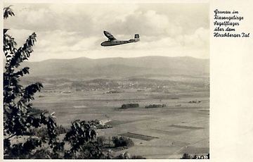 Szybowiec nad Jelenią Górą, w tle panorama Karkonoszy. Na ogonie ma swastykę. Pocztówka pochodzi z okresu po 1933 roku.