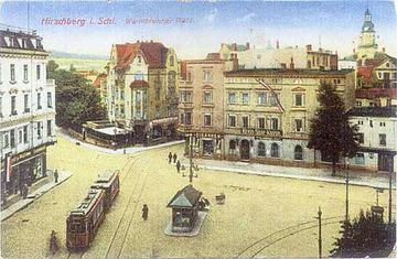 Warmbrunnerplatz z perspektywy okna okolicznych kamienic. Widoczny przystanek tramwajowy z kioskiem i po prawej – budka meteorologiczna.