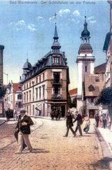 Belle epoque na Schlossplatz. Przed dzwonnicą kościoła św. Jana Chrzciciela nieisteniejące już dziś zabudowania. Zostały wyburzone pod budowę domu zdrojowego.