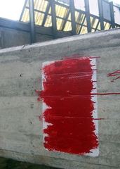 Zamalowane ostrzeżenie przed niebezpieczeństwem pod estakadą.