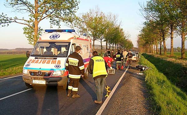 Ratownicy udzielają pomocy rannemu motocykliście.