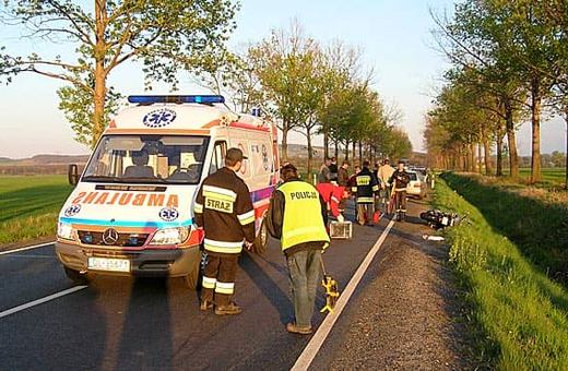 Ratownicy udzielają pomocy rannemu motocykliście.