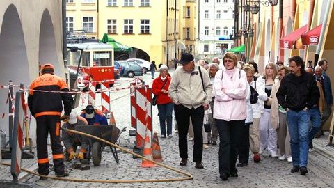 Niemieccy turyści zwiedzają miasto przy ogłuszającym huku młotów pneumatycznych.