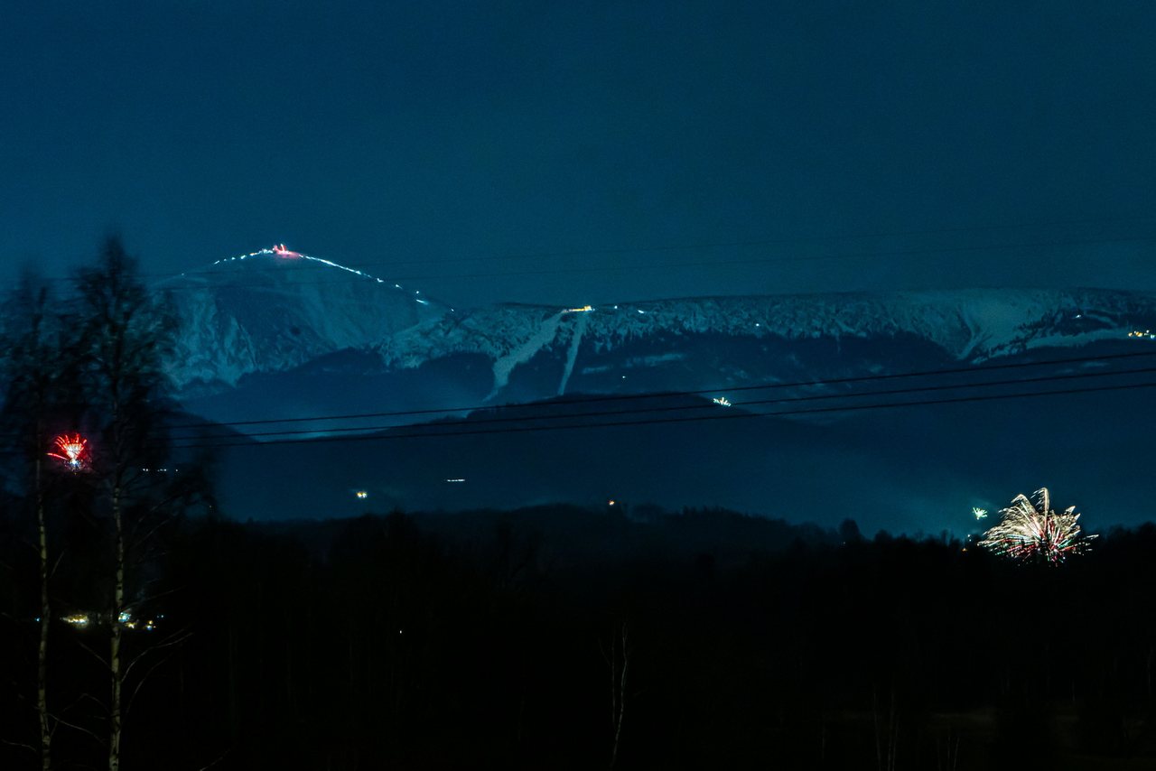 Panorama ośnieżonych Karkonoszy i rozświetlonej Śnieżki nocą