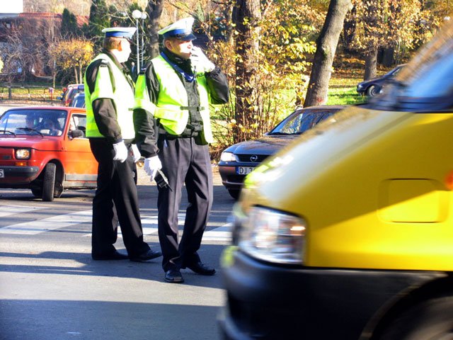 Policjanci kierują ruchem przed cmentarzem komunalnym.