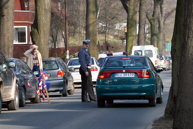 Policjant wskazuje kierowcom, jak ominąć dziurę.