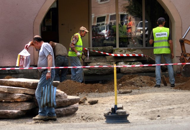Robotnicy w upalne przedpołudnie pracują przy remoncie nawierzchni lubomirskiego rynku.