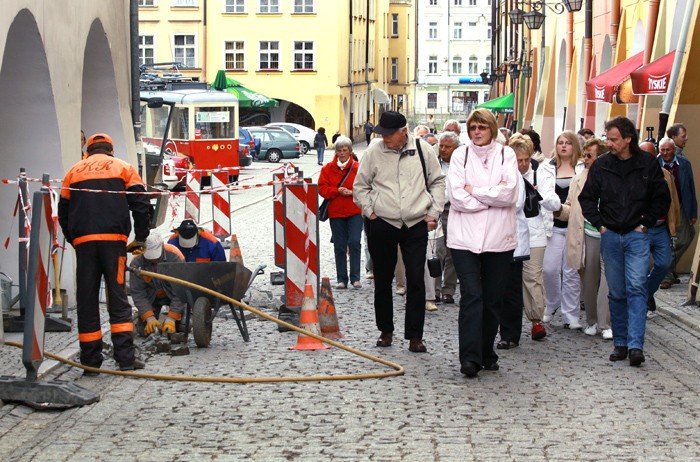 Niemieccy turyści zwiedzają miasto przy ogłuszającym huku młotów pneumatycznych.