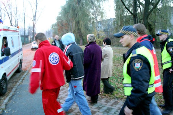 Strażnicy i ratownicy pogotowia prowadzą nastolatka do ambulansu.