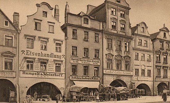 Rynek na początku wieku XX. Dwuwagonowy tramwaj podąża na ulicę Długą. Kupcy przywożą towar wozami.