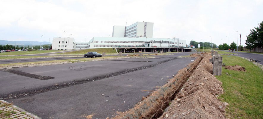 Koparka niweluje teren parkingu przed szpitalem: tu będą lądować śmigłowce.