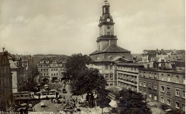Przed ratuszem zielenią się kasztanowce, tramwaj z wagonem doczepnym zmierza w stronę placu Cieplickiego. Na rynku – stoiska handlowe. Pełnia życia w centrum miasta. Przełom lat 20 i 30 minionego wieku.
